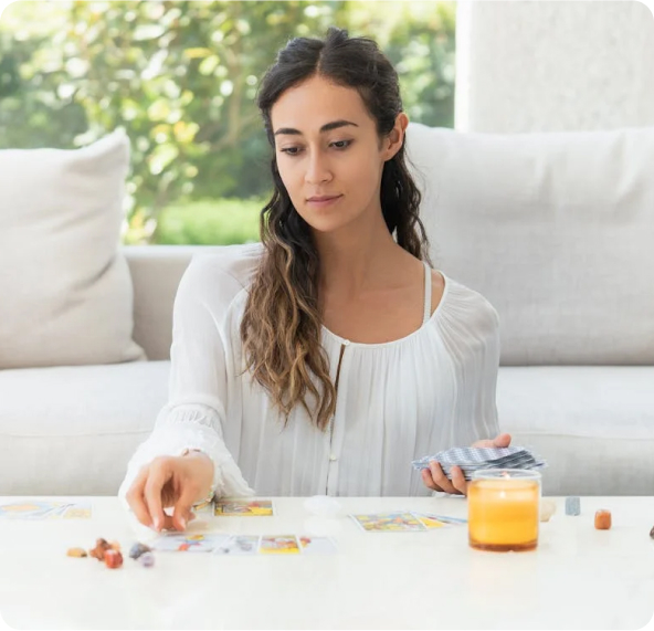 woman sitting at a white table reading tarot cards
